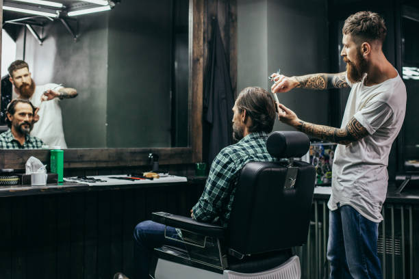 istock Barbershop visitor looking at his reflection while bearded barber working 1083857898