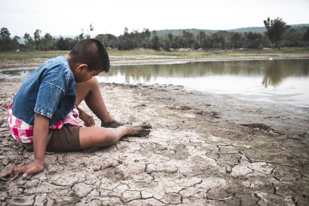 istock Rear View Of Boy Sitting On Drought Land 1083863066