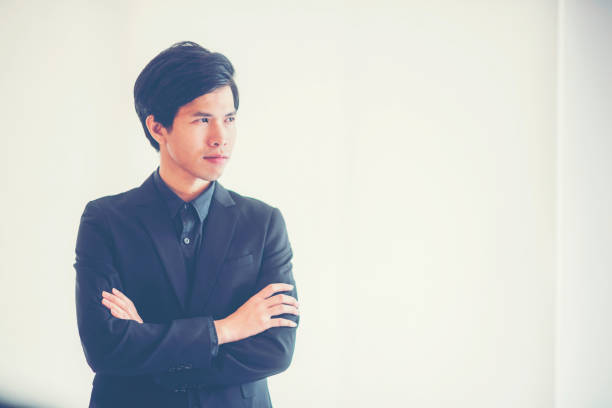 istock Businessman Standing With Arms Crossed Against White Wall 1083868672
