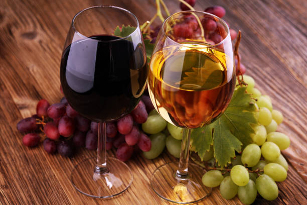istock White wine and red wine in a glass with fall grapes on rustic background. 1083879044