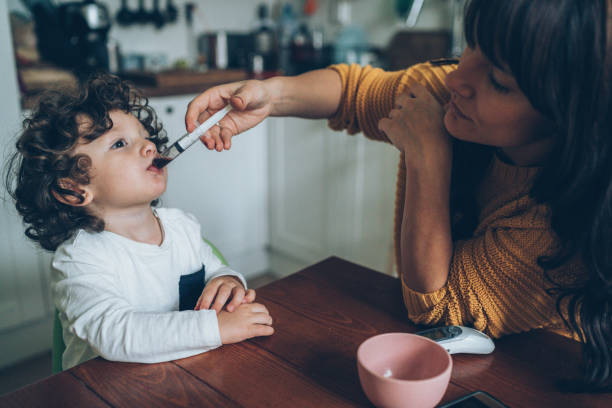 Mother giving syrup to her son Mother giving syrup with syringe to her cute little son child liquid medicine stock pictures, royalty-free photos & images