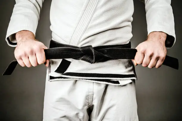 Photo of Midsection of Man in A Gi holding Black Belt