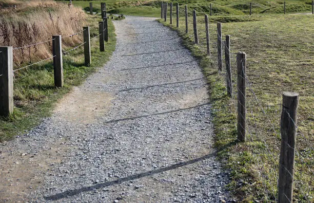 A dirt and gravel path with a wire fence.