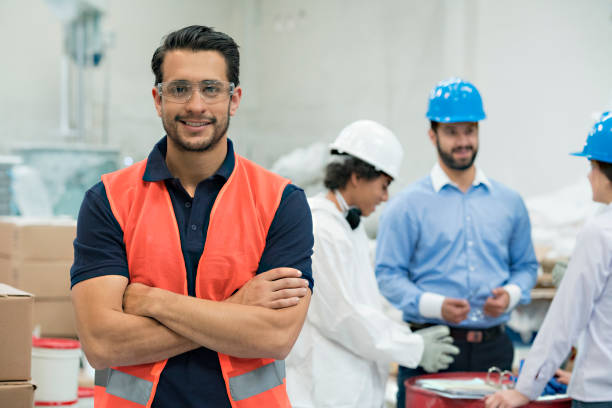 Group of workers in a factory Group of engineers and workers, discussing the working model of the day, all very focused, while there is one standing in front of the camera smiling manufacturing occupation stock pictures, royalty-free photos & images