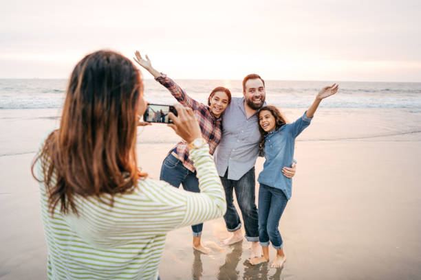 istock Family on the beach taking photos 1083896556