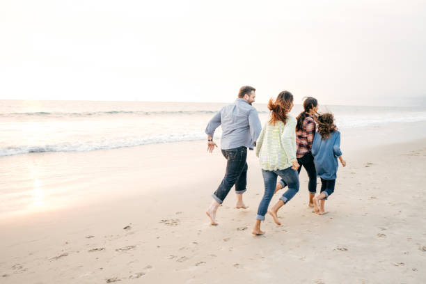 istock Two parents and two kids running on the beach 1083896560