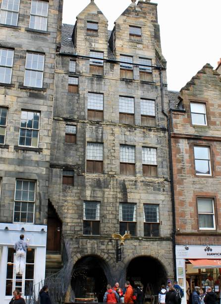 Edinburgh, Scotland - March 27, 2018: Gladstone's Land is a 17th-century surviving high-tenement house that is located along the Royal Mile in Old Town. The building was first constructed in 1617 and today it has become a popular tourist attraction. Above the entrance hangs its iconic sign with a gilt-copper hawk hovering above.