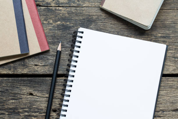 istock Top view blank notebook paper and pencils on old wooden table 1083930502