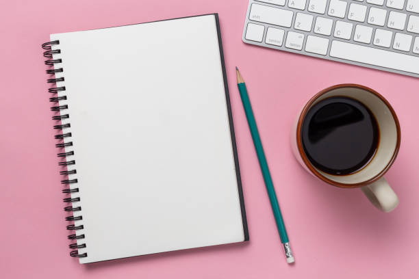 istock Top view, empty notebook and office supplies on the desk pink background 1083930696