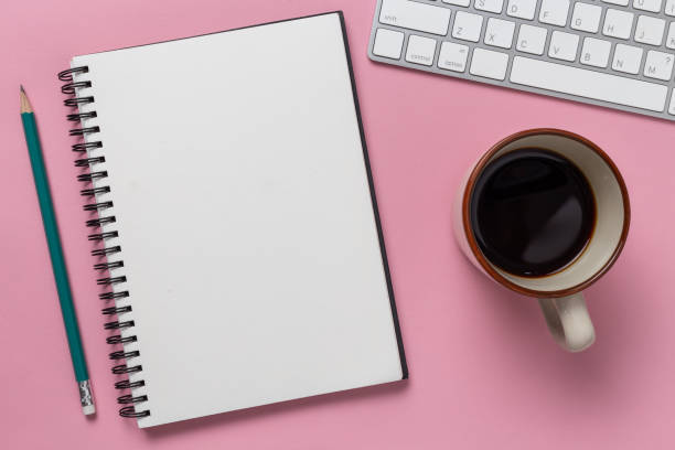 istock Top view, empty notebook and office supplies on the desk pink background 1083930748