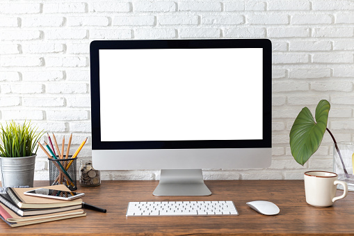 espacio de trabajo con computadora con pantalla blanca en blanco y suministros de oficina en un escritorio de madera photo