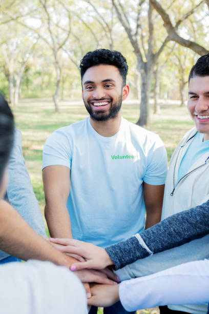 istock Community cleanup volunteer stacks hands with team 1083936346