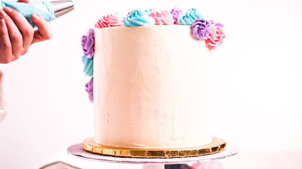 istock Baker piping pastel color buttercream rosettes on a white cake 1083947432
