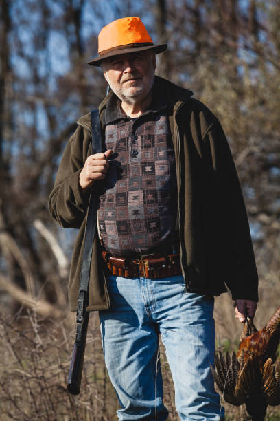 istock Elderly hunter with wild bird in orange hat 1083956630