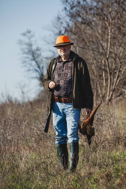 istock Elderly hunter with wild bird in orange hat 1083956654