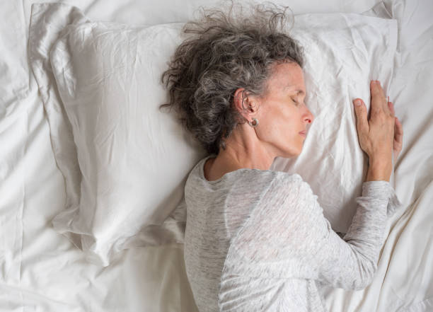 istock Middle aged woman sleeping on silk pillow case from above 1083958208