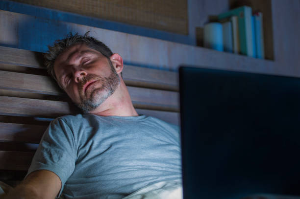 istock young tired and exhausted internet or work addict man sleeping while networking late night with laptop computer on bed in overwork and social media addiction concept 1083963118