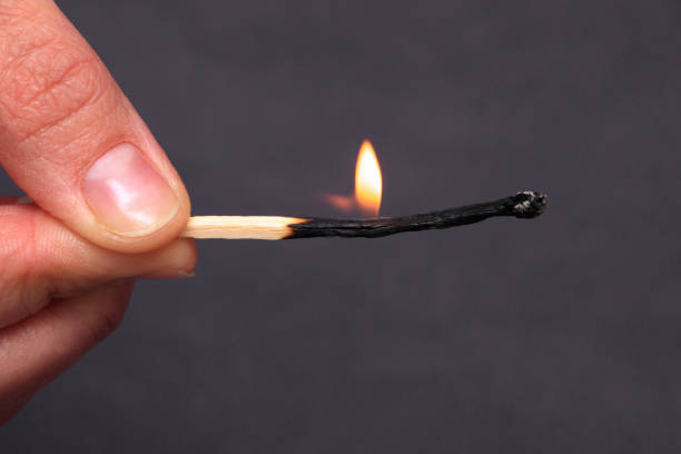 istock Burning match in female hand, isolated on black 1083980700