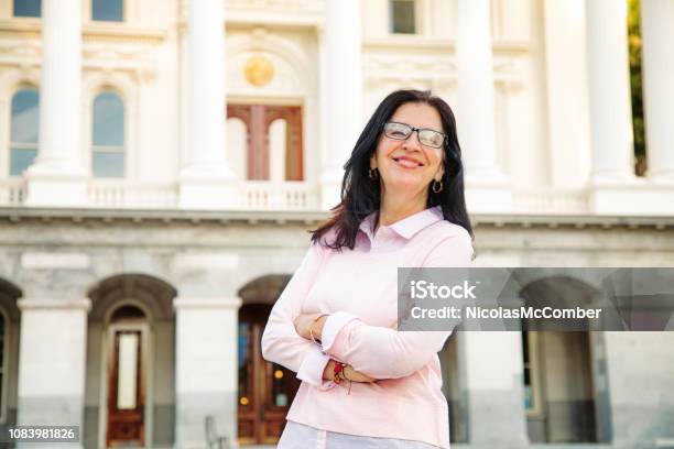 Confident Middle Aged Beautiful Smiling Latina Woman Portrait By Government Building Stock Photo - Download Image Now