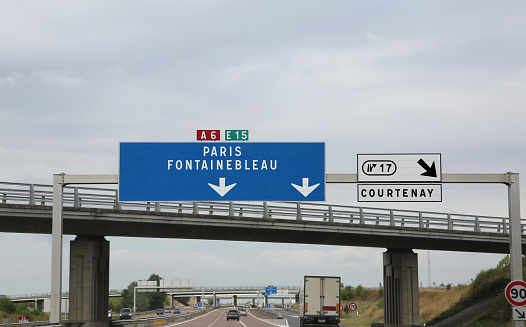 big road signs on the busy French highway to go to Paris and Fontainebleau or Courtenay city