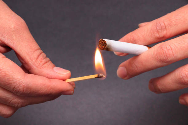 istock Woman hand burning a cigarette with a match 1083996994