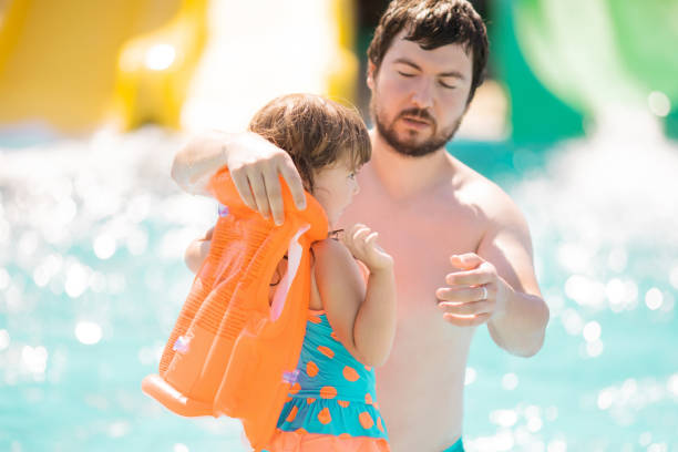 pai, ajudando sua criança bonita filha wuth seu colete salva-vidas na piscina ao ar livre no parque aquático (parque aquático) - life jacket life belt buoy float - fotografias e filmes do acervo