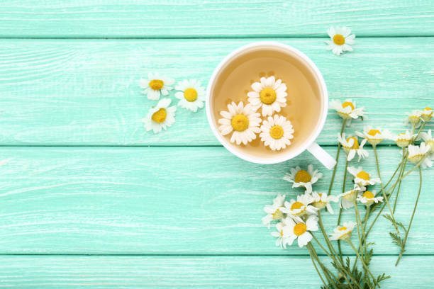 istock Cup of tea with chamomile flowers on mint wooden table 1084021506