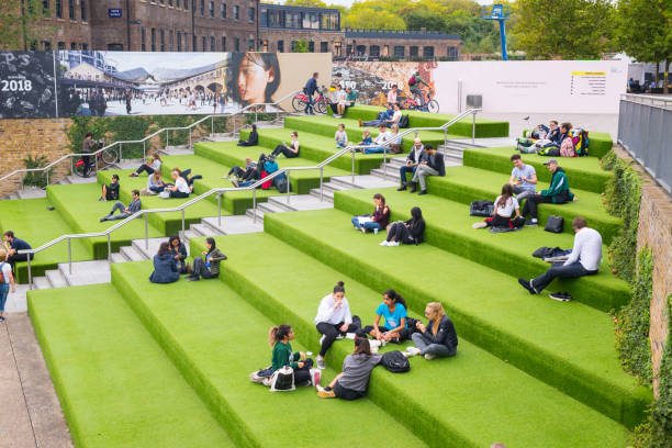 London, UK - October 2017: Young People students sitting outdoor on Granary Square steps. Granary Square is a public square on the banks of Regent’s Canal in the heart of King’s Cross, London, UK