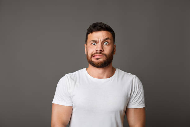 Muscular man grimacing guilty face at studio Oops. Muscular caucasian man grimacing guilty face at studio background grimacing stock pictures, royalty-free photos & images