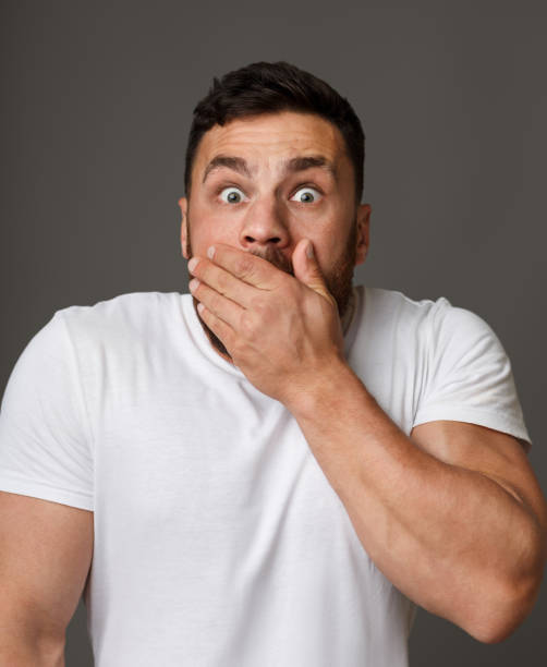 istock Amazed man covering his mouth over gray background 1084031528