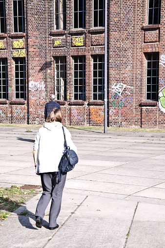 A couple admires Hochofenplatz - a decommissioned steel factory - while walking past a graffiti-covered brick wall in Phoenix West, Dortmund - Germany