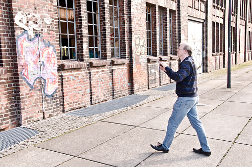 A man admiring Hochofenplatz - a decommissioned steel factory - and an old building with graffiti-covered brick wall in Phoenix West, Dortmund - Germany