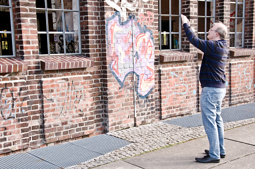 A man admiring Hochofenplatz - a decommissioned steel factory - and an old building with graffiti-covered brick wall in Phoenix West, Dortmund - Germany