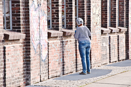 A female cyclist admiring Hochofenplatz - a decommissioned steel factory - and an old building with graffiti-covered brick wall in Phoenix West, Dortmund - Germany