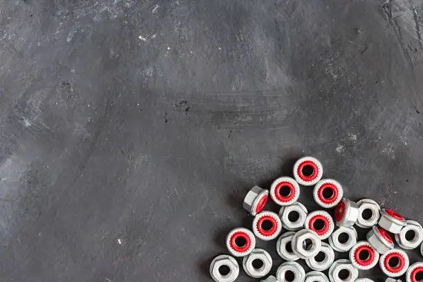 Metal grey and red inside seal locks for hermetization of carving for liquid and gas fluid on the right lower part of oblong horizontal shot made from the top view on the black rustic background