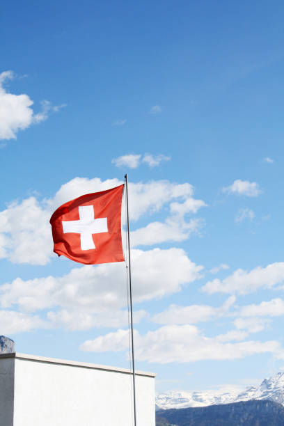 istock Swiss flag. Blue sky background. Sunny day with clouds. 1084034342