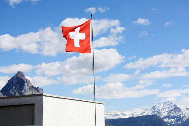 istock Swiss flag. Blue sky background. Sunny day with clouds. 1084036538