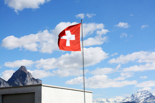 istock Swiss flag. Blue sky background. Sunny day with clouds. 1084036546