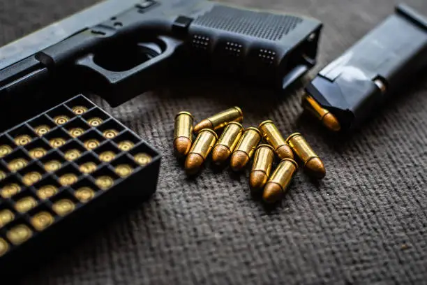 Photo of bullets and gun on black velvet desk