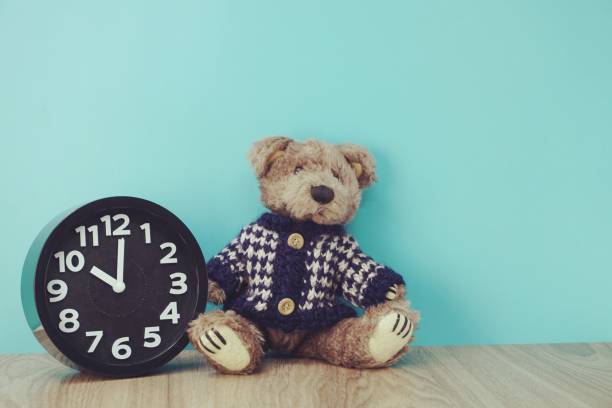 istock teddy bear and alarm clock with space copy on wooden background 1084041254