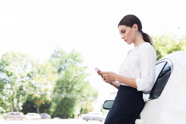 istock Business woman using smartphone, leaning on car 1084043132
