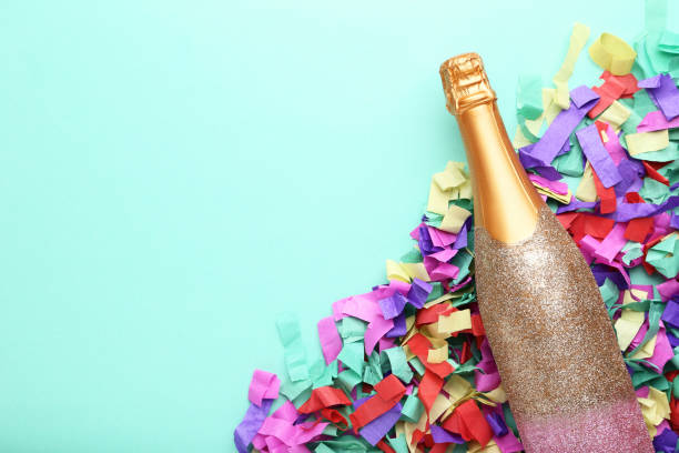 istock Champagne bottle with colorful confetti on mint background 1084046498