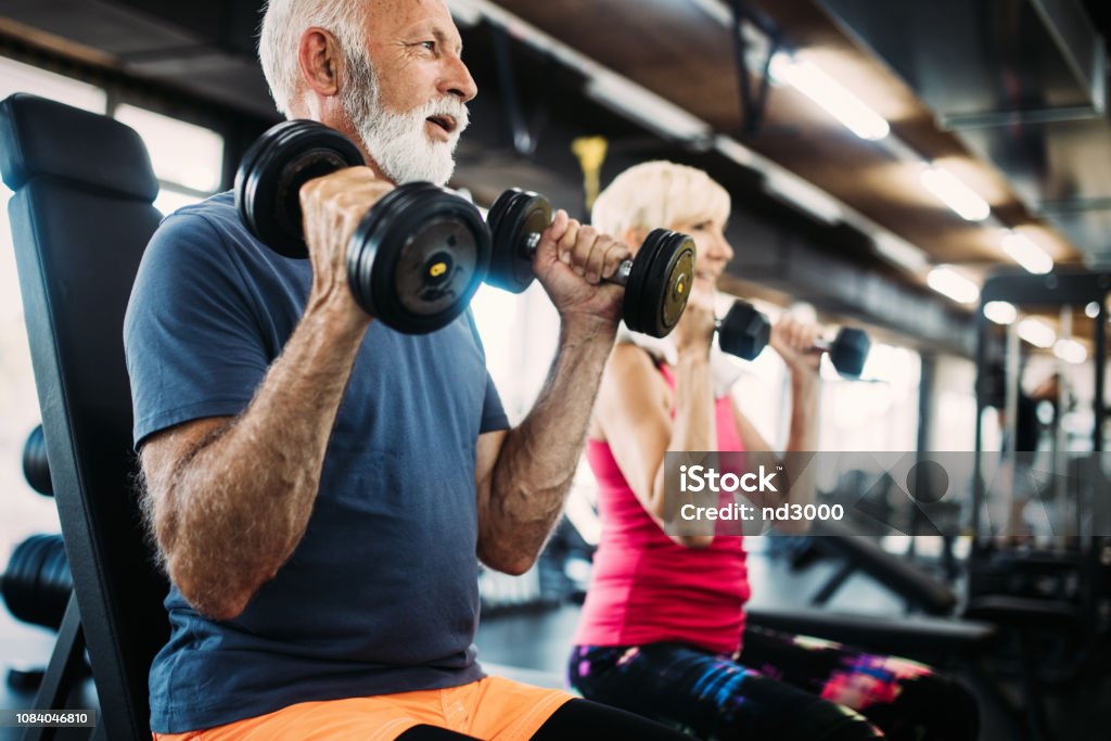 Senior fit man and woman doing exercises in gym to stay healthy Mature fit man and woman doing exercises in gym to stay healthy Exercising Stock Photo