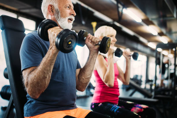 старший подходят мужчина и женщина делают упражнения в тренажерном зале, чтобы оставаться здоровым - exercising sport gym spinning стоковые фото и изображения