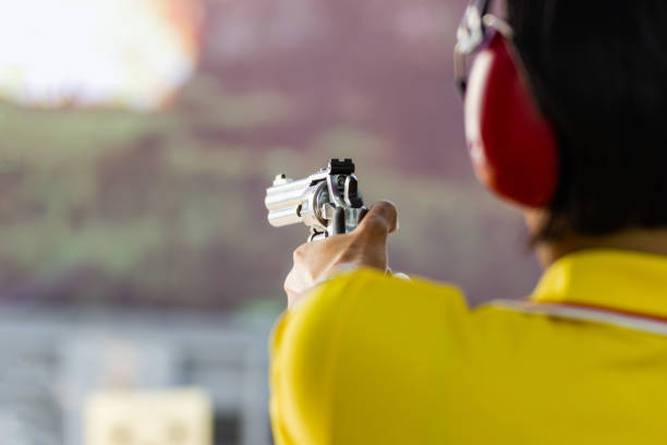 Man hold a gun ready to shoot  practicing shooting in the park selective focus on the back part of gun