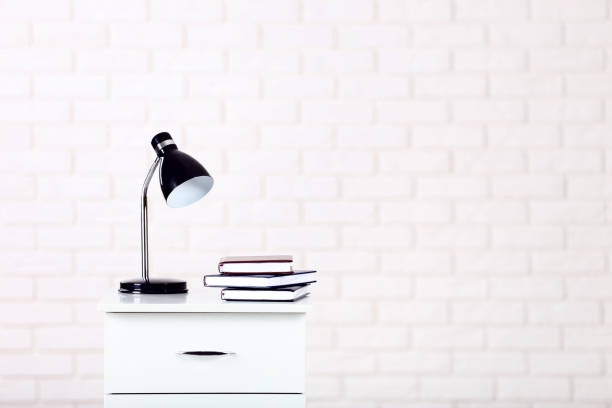 istock White bedside table with lamp and books on brick wall background 1084048876