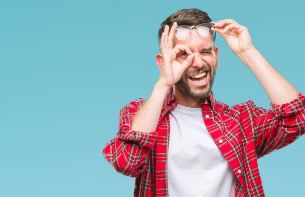 istock Young handsome man over isolated background doing ok gesture with hand smiling, eye looking through fingers with happy face. 1084051060