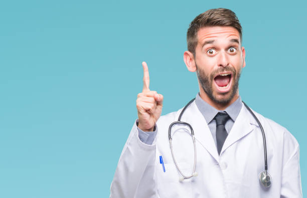 istock Young handsome doctor man over isolated background pointing finger up with successful idea. Exited and happy. Number one. 1084051218