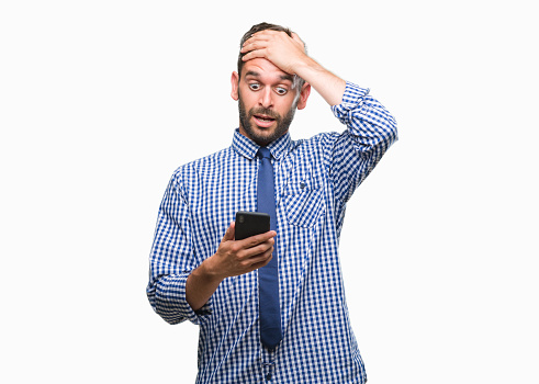 Young hadsome man texting sending message using smartphone over isolated background stressed with hand on head, shocked with shame and surprise face, angry and frustrated. Fear and upset for mistake.
