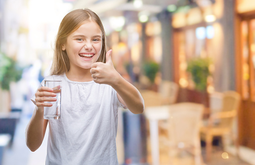 Young beautiful girl drinking glass of water over isolated background happy with big smile doing ok sign, thumb up with fingers, excellent sign